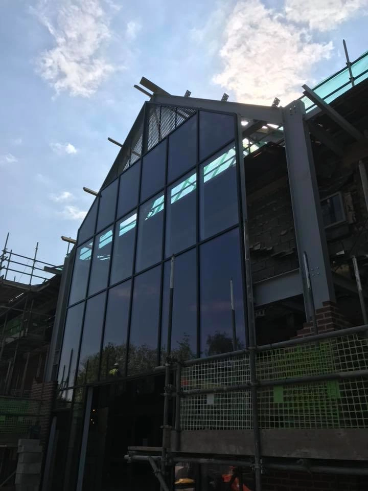 An architectural steel fabrication receiving its glass front paneling.