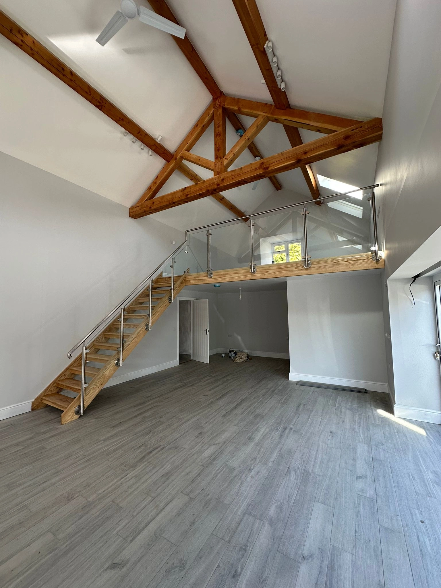 showing a mezzanine platform with glass and stainless steel, finished with a wooden staircase and handrail.