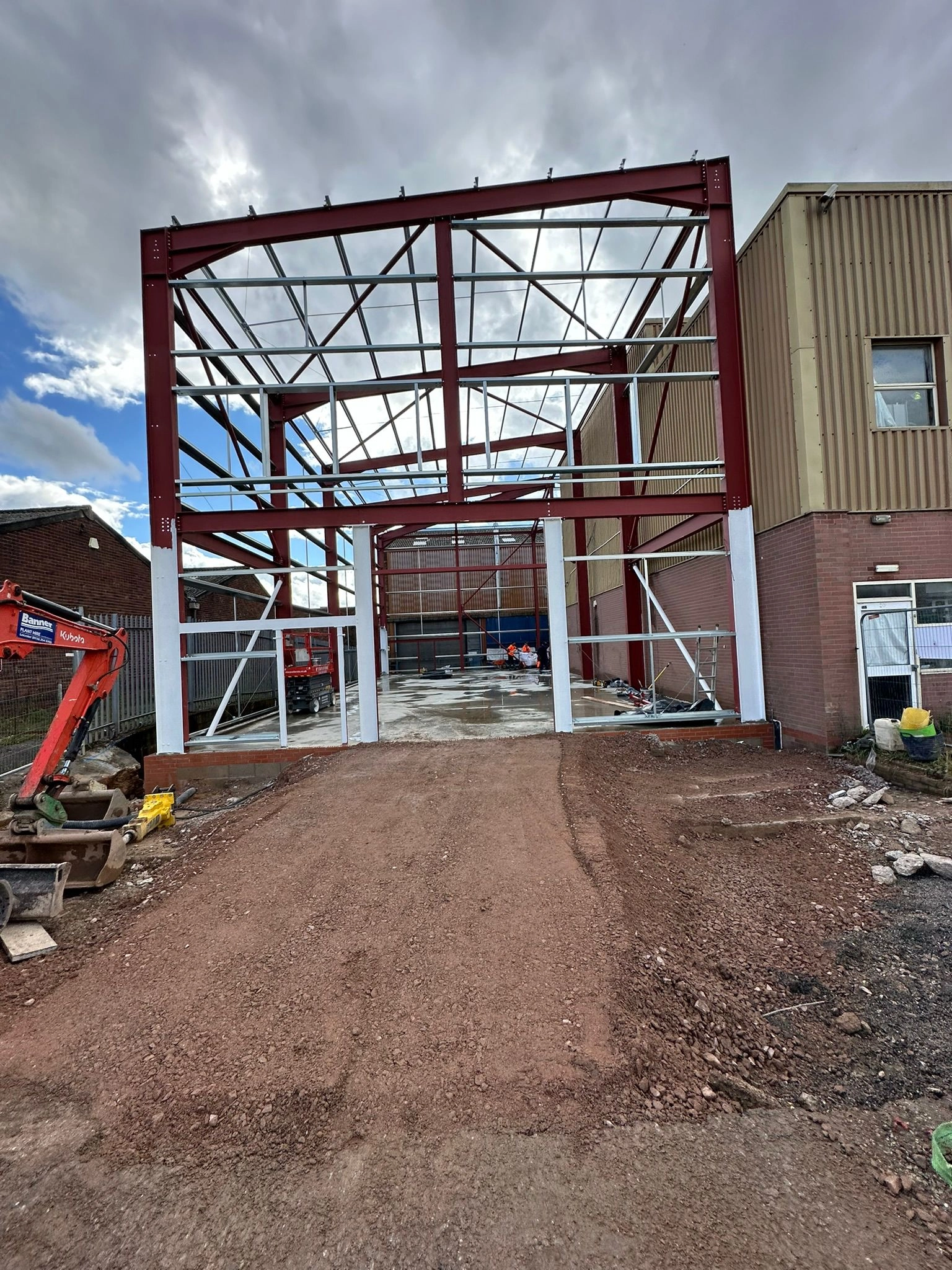 Steel Structural portal frame building with pre-fabricated structural steel columns, beams, and secondary galvanized framing, an extension for an industrial warehouse.